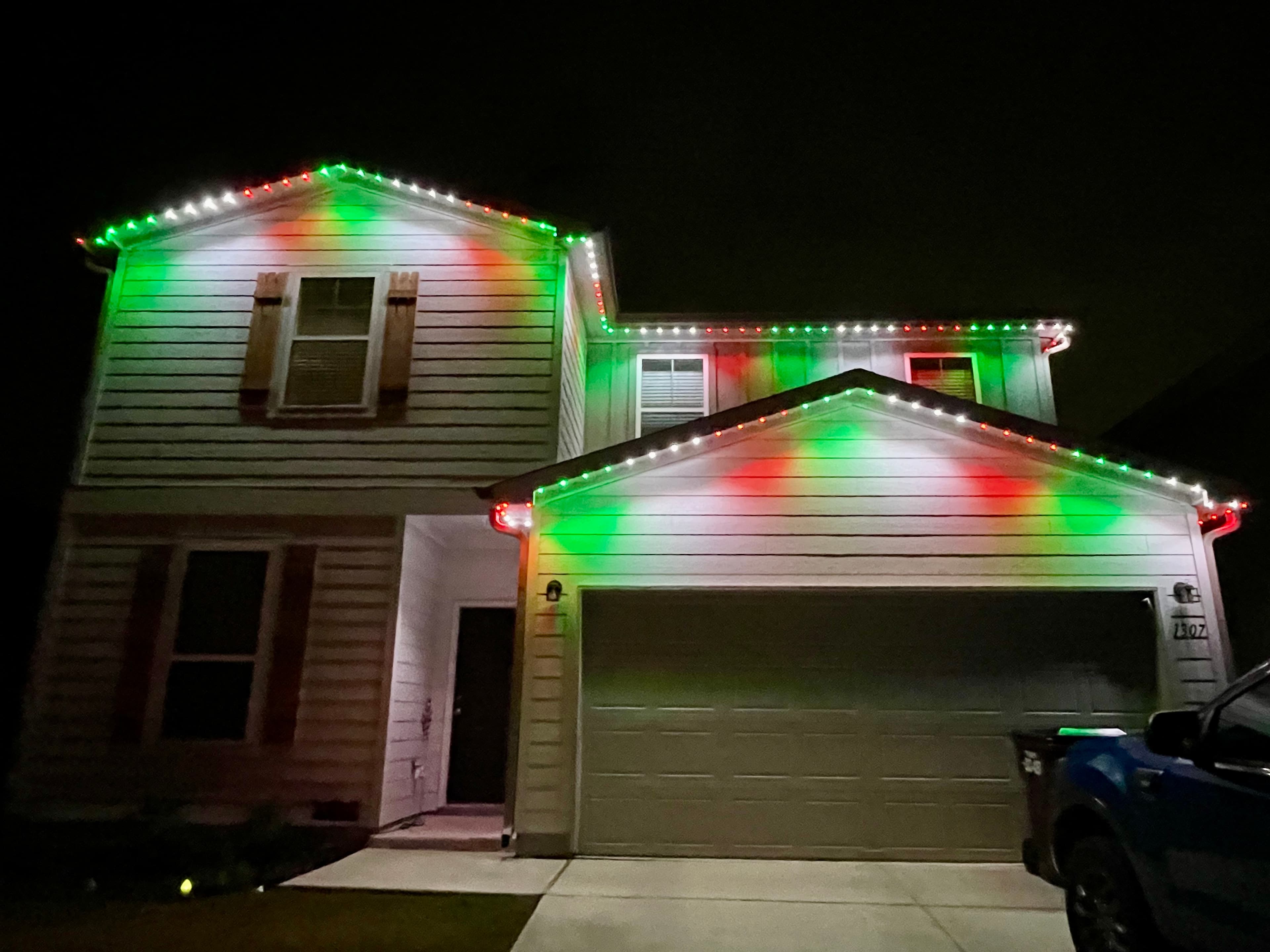 Customer-supplied LIT365 installation: main gables and garage of a home under red, green, and white permanent lighting at night