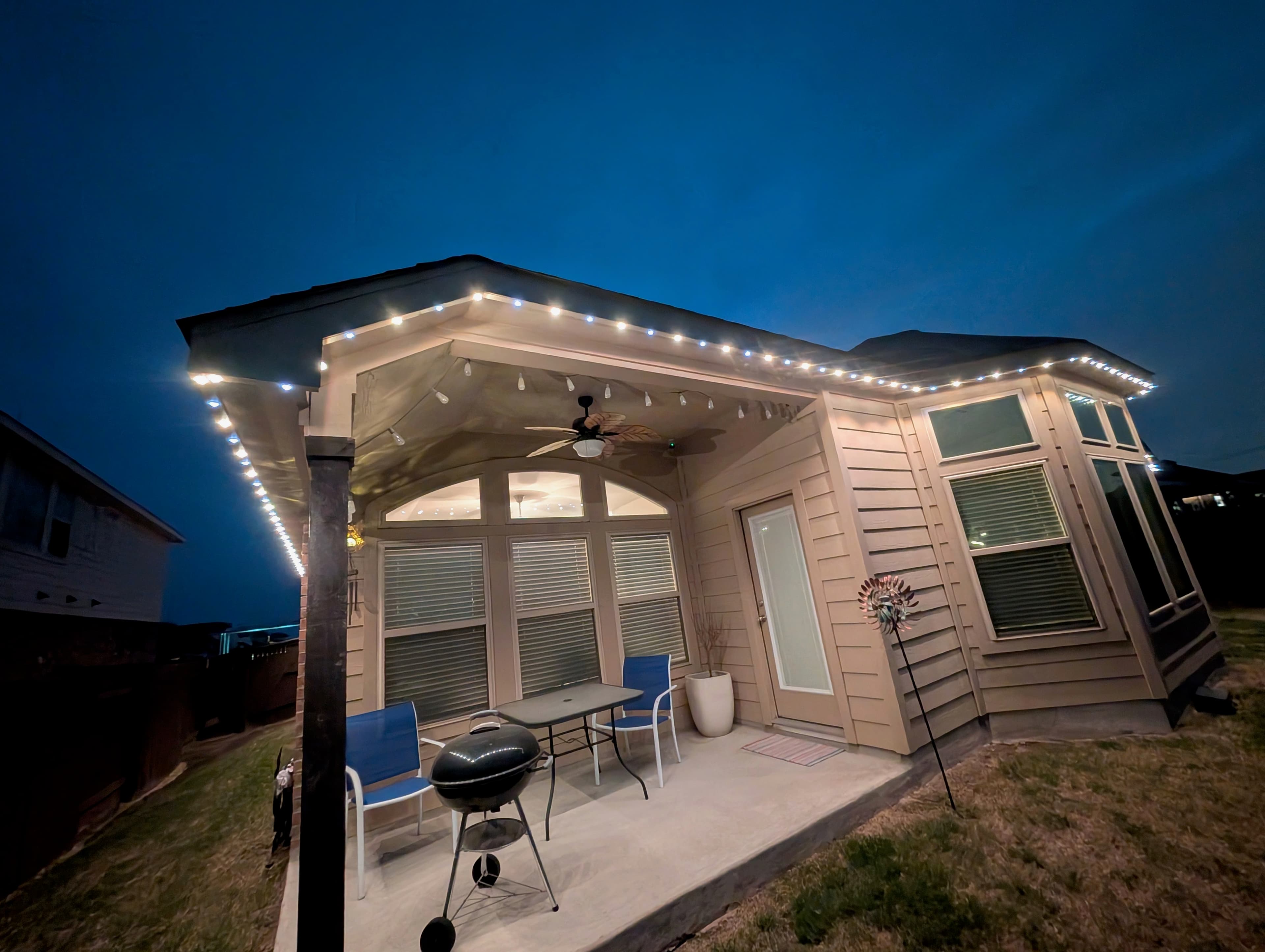 Customer-supplied LIT365 installation: a backyard patio structure with warm permanent lighting along its eaves at dusk