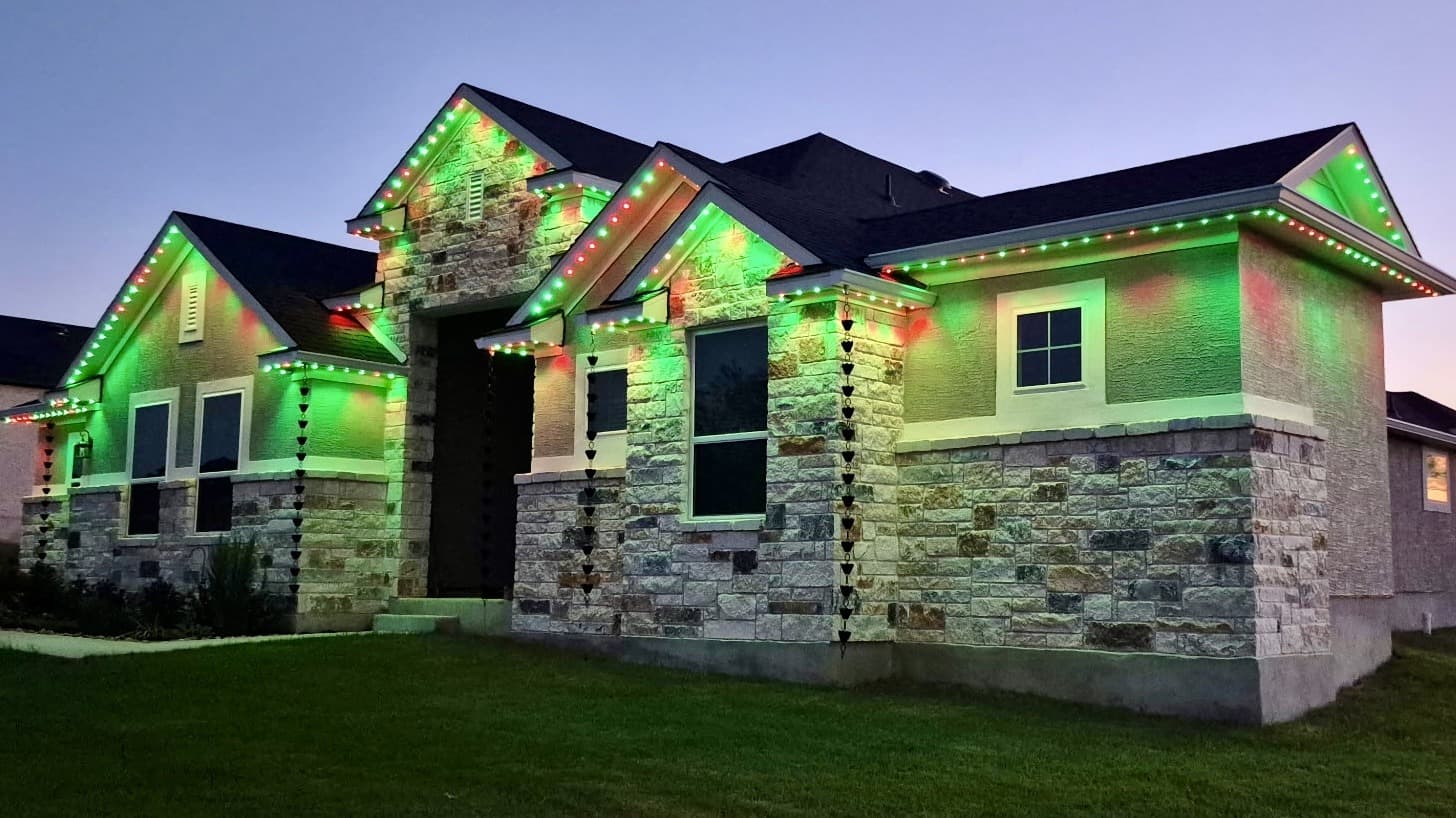 Customer-supplied LIT365 installation: a home's facade and roofline washed in a green permanent-lighting scene at night