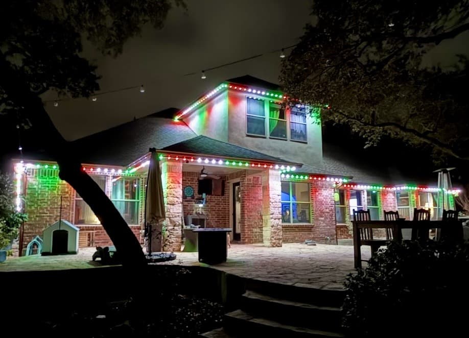 Customer-supplied LIT365 installation: lit gables and garage of a home traced in permanent roofline lighting at night