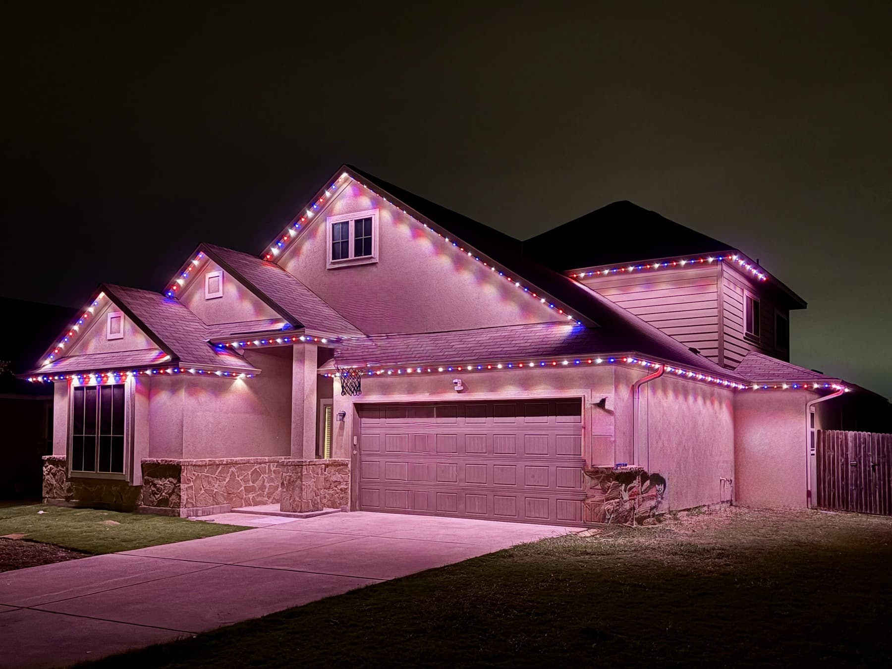 Customer-supplied LIT365 installation: a full house under a pink-and-magenta permanent-lighting scene at night