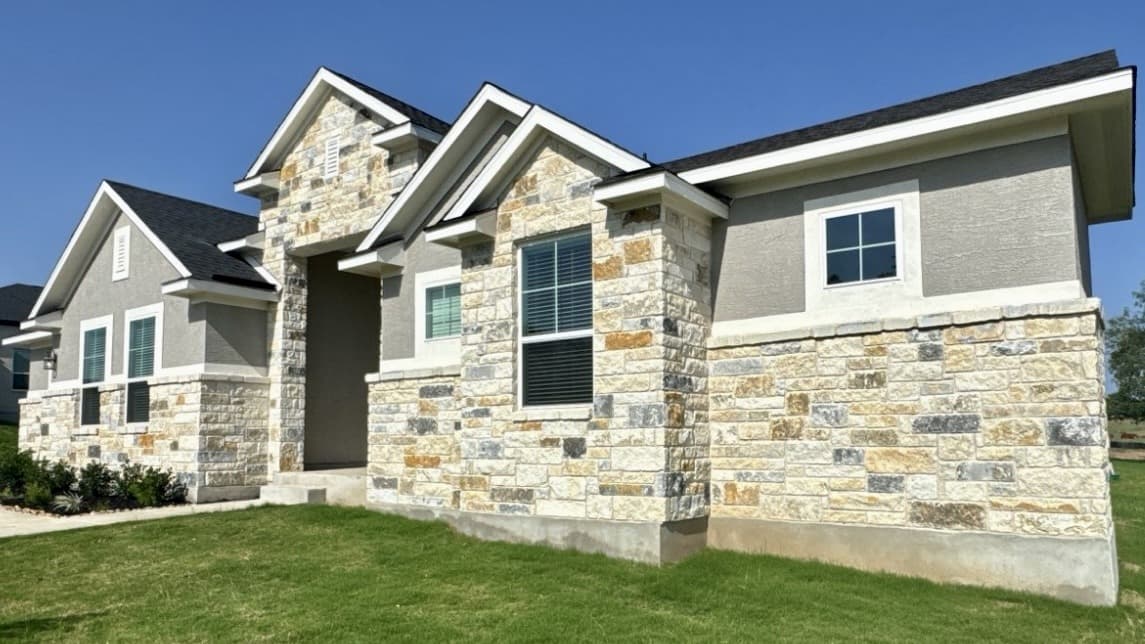 Customer-supplied daytime photo of a stone home showing its complete facade, eaves, and lawn