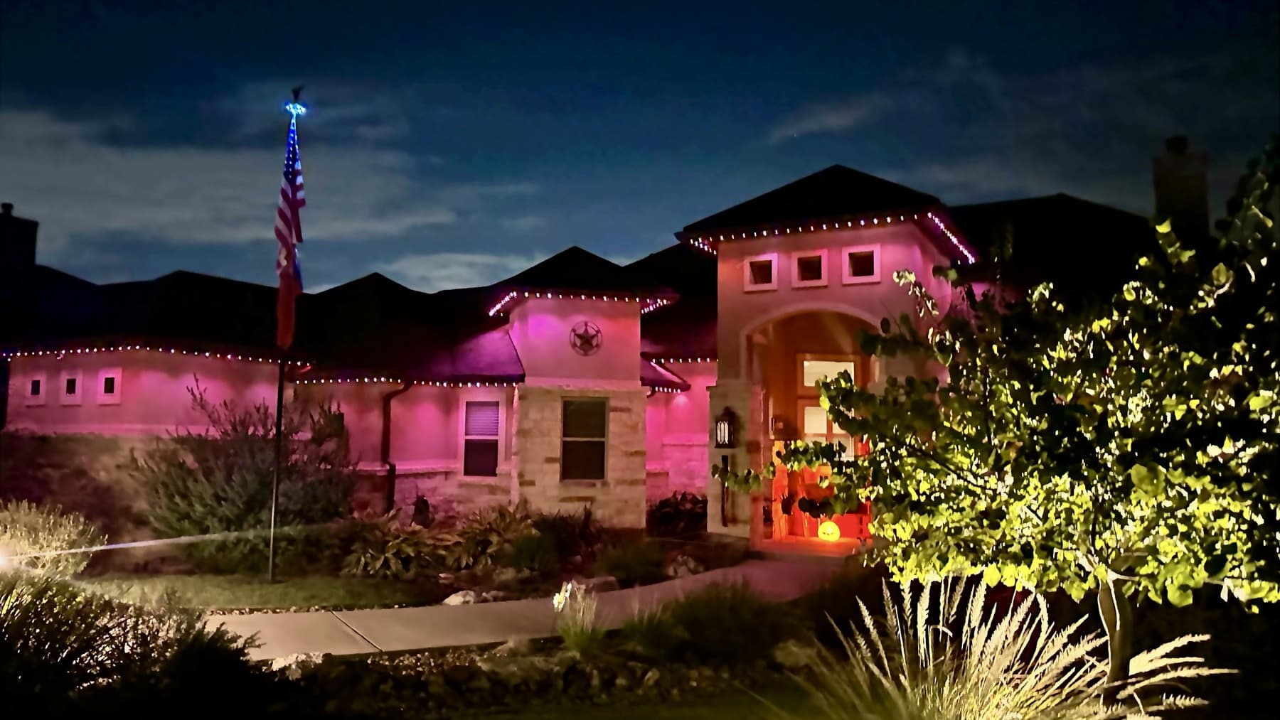 Representative customer-supplied LIT365 installation for the Austin service market: a lit facade with a flag, under warm permanent roofline lighting