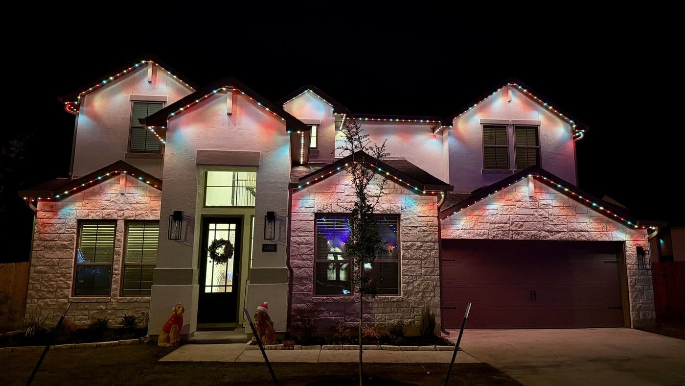 Home with multicolor permanent holiday roofline lighting at night