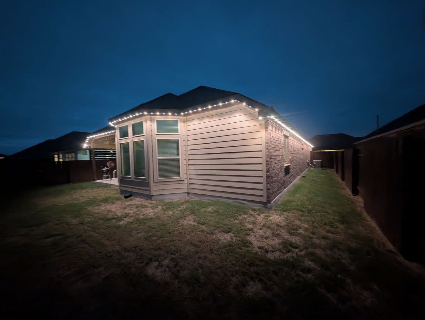 Home exterior evenly lit by warm white permanent roofline lighting
